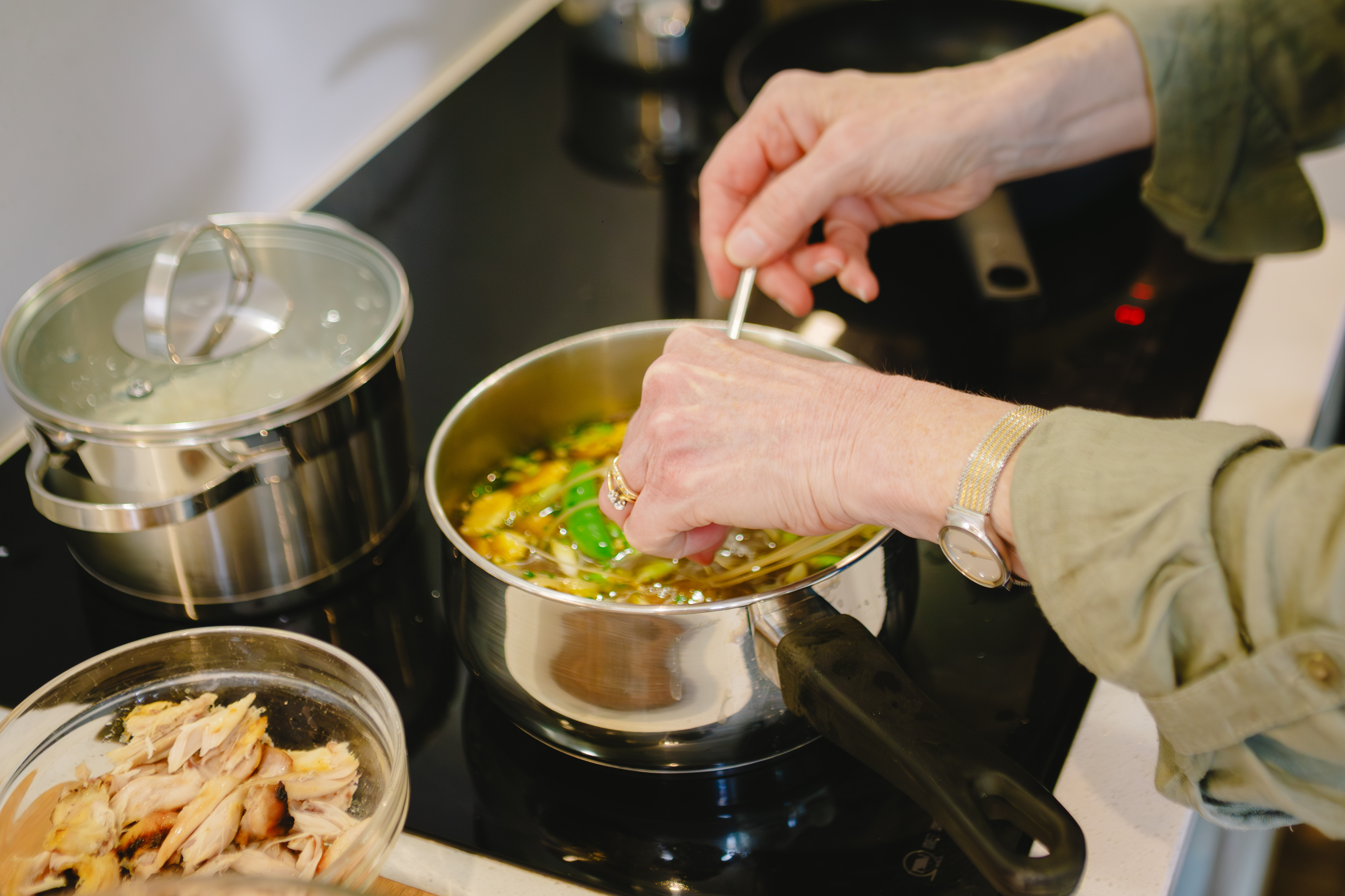 Hands stirring a pot in an Asian cooking class